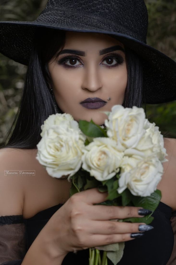 Portrait in a black hat holding white roses
